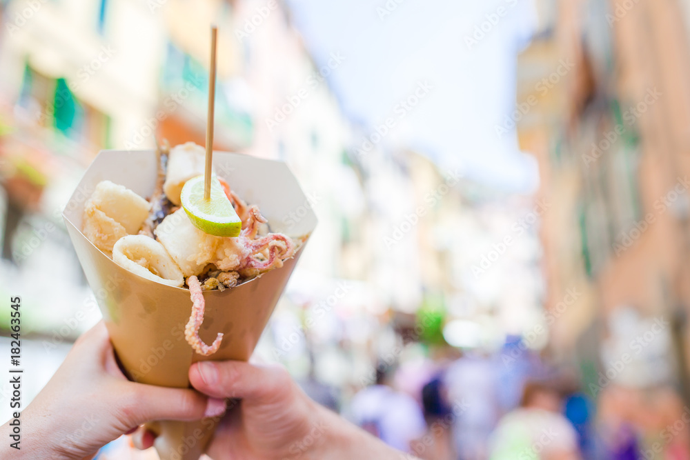 Italian street food grilled seafood fish, shrimps, calamari and vegetables.  Hands of couple holding a seafood cone with lemon in Cinque Terre in Italy  Stock Photo | Adobe Stock