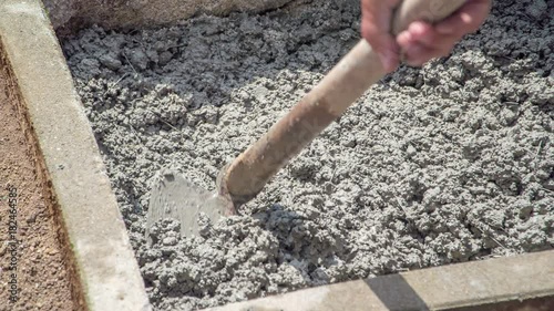 Arranging concrete evenly into smaller eclosed area with a help of a hoe. photo