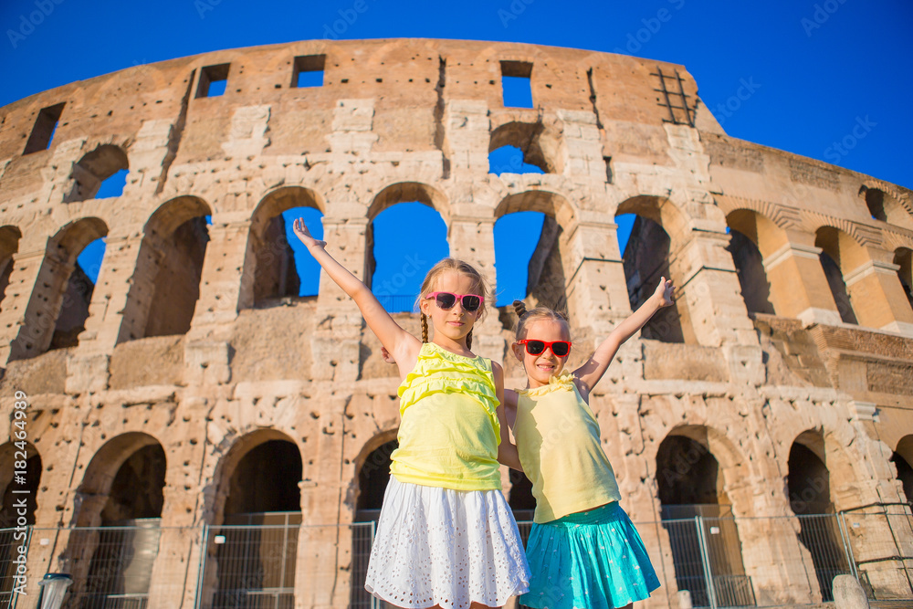 Adorable fashion little girls outdoors in European city. Kids background the famous Colosseum in Rome, Italy.