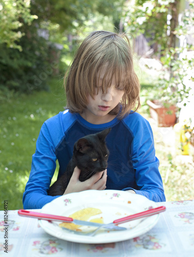 Boy Holdning a Cat at the Table. photo