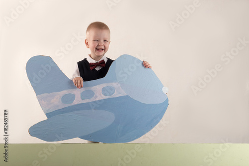 A happy child is holding a cardboard plane and an empty banner. Greeting card with Christmas. The concept of Christmas holidays