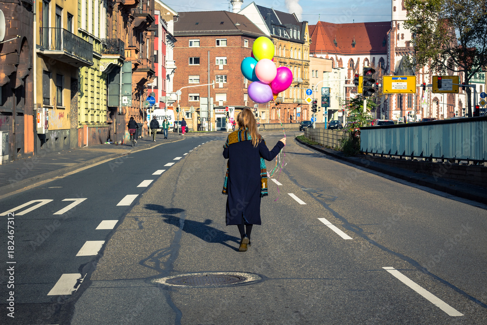 woman walking in the city with colorful helium balloons