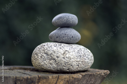 Canvas Print Three zen stones pile on wooden stump, white and grey meditation pebbles tower