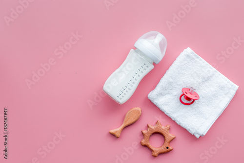 Little baby background. Wooden toys, pacifier, bottle, towel on pink background top view copyspace