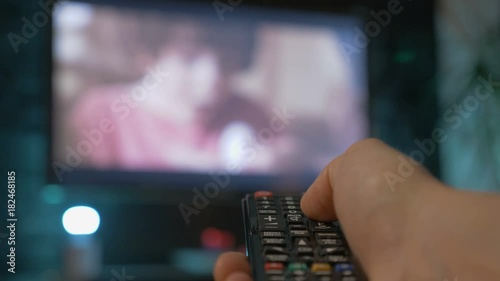 Close up man hand holding the TV remote control and changing channels.