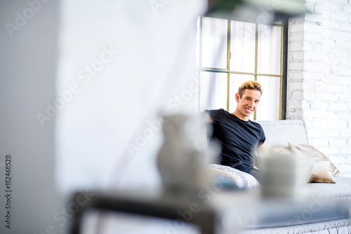 A young handsome man relaxing on the sofa in a loft style apartm photo