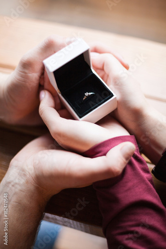 Fotografija Ring with a diamond in a box, the hands of a girl and a guy, close-up