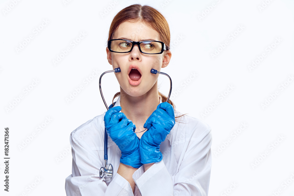 Young beautiful woman in glasses and in medical robe holds a stethoscope on white isolated background, doctor.medicine, emotions Young beautiful woman in glasses and in medical robe holds a stethoscope on white isolated background, doctor.medicine, emotions
