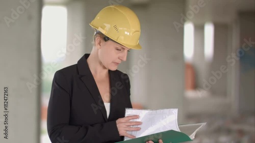 Female architect looking at blueprints at construction site photo