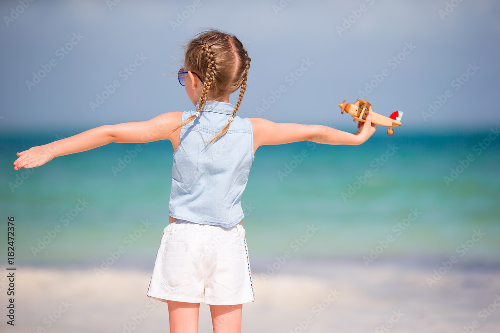 Happy child girl playing with toy airplane on the beach. Kid dream of becoming a pilot Happy child girl playing with toy airplane on the beach. Kid dream of becoming a pilot