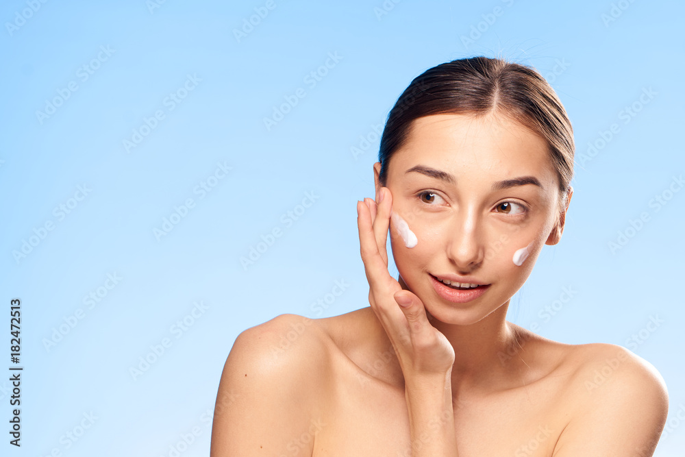 Young beautiful woman on a blue background, cosmetic cream, health, beauty, portrait Young beautiful woman on a blue background, cosmetic cream, health, beauty, portrait