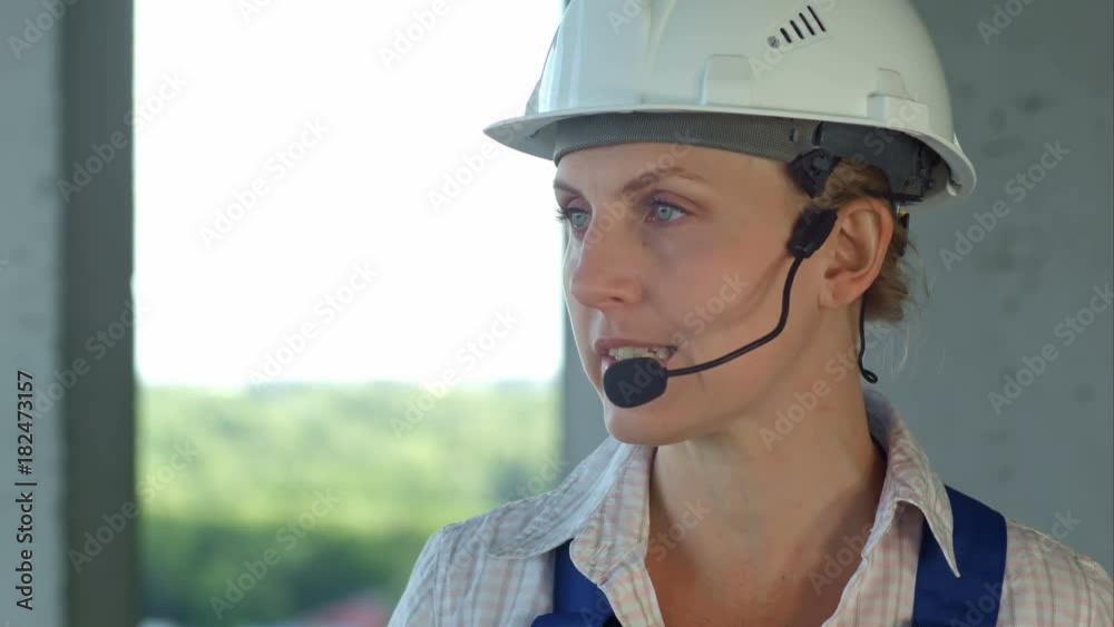 Female builder engineer is considering a plan for new construction and talking via microphone Female builder engineer is considering a plan for new construction and talking via microphone