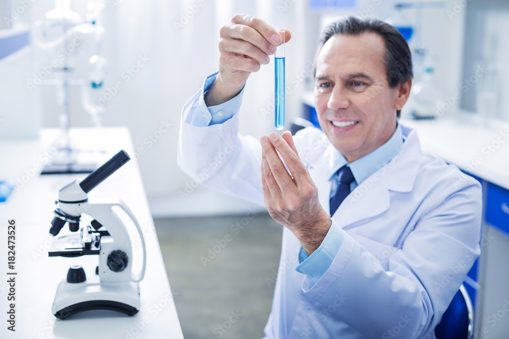 Chemical laboratory. Selective focus of test tube with blue liquid being in hands of a smart nice male scientist Chemical laboratory. Selective focus of test tube with blue liquid being in hands of a smart nice male scientist