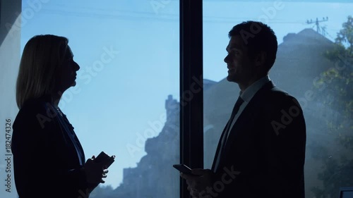 Slow motion footage of business people shaking hands and chatting in the office / Business people shaking hands