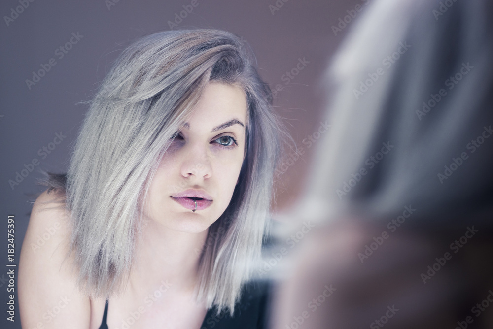 Beautiful young woman looking in the mirror Beautiful young woman looking in the mirror