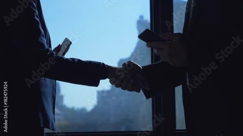 Slow motion footage of business people shaking hands and chatting in the office / Business people shaking hands