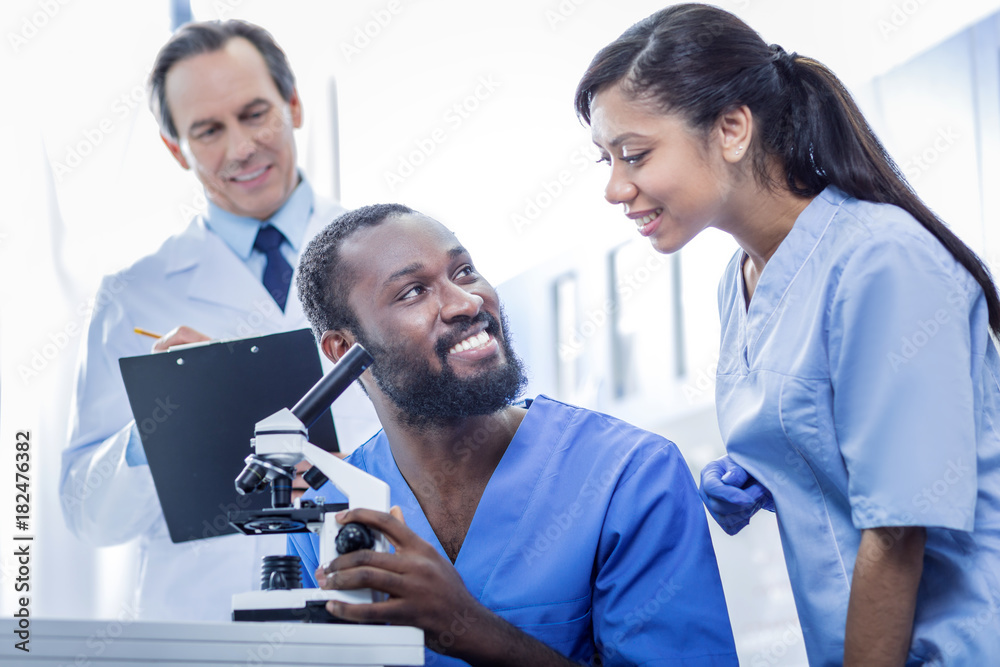 Fototapeta premium Team of professionals. Joyful nice smart doctors being in the lab and working together while being a team