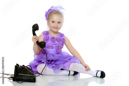 The girl is talking on the old phone.