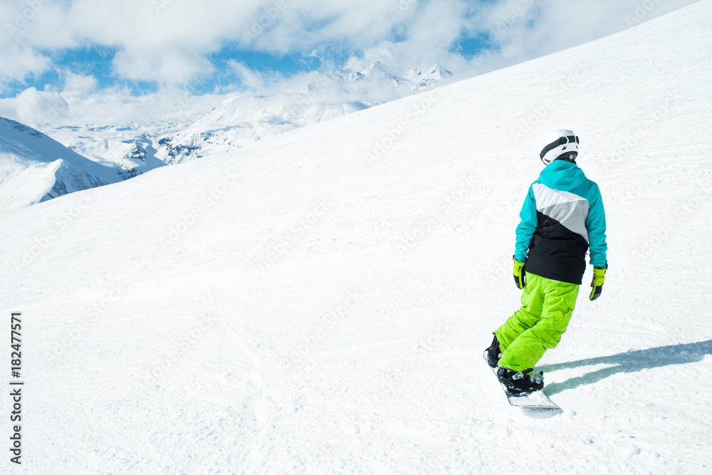 Snowboarder woman on background landscape of snowy high mountains