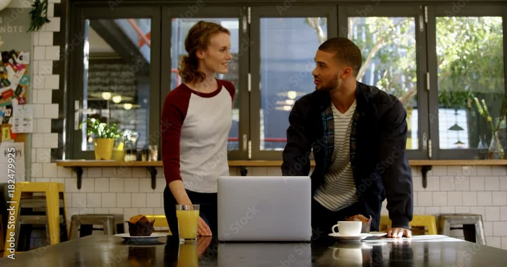 Man and woman executive discussing over a laptop in office cafeteria Man and woman executive discussing over a laptop in office cafeteria