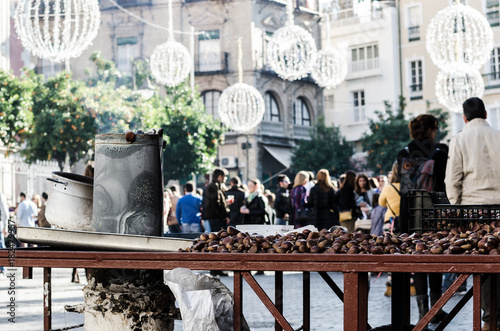 Roasted chestnuts stand in Seville downtown during Christmas eve in a crowded street