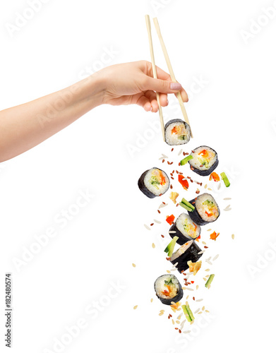 Falling pieces of sushi and sushi roll with wooden chopsticks in female hand, isolated on white background