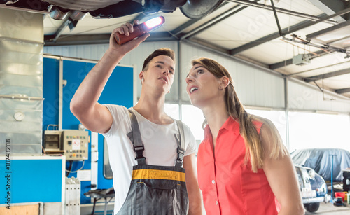 Low-angle view of an experienced auto mechanic checking the disk brake rotors of the car of a female customer, in a modern automobile repair shop