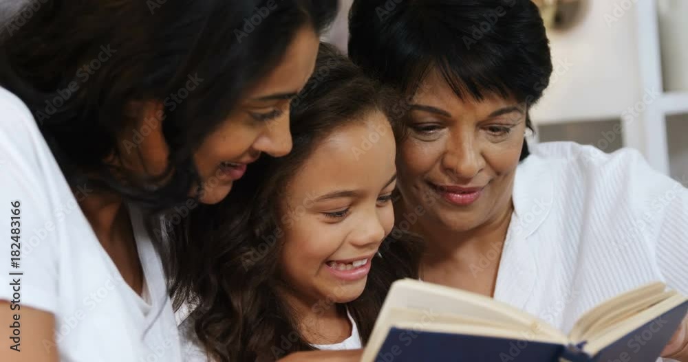 Multi-generation family reading a book in bedroom Multi-generation family reading a book in bedroom