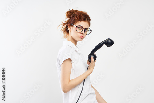 Young woman on a white background holds a landline phone, communication, search