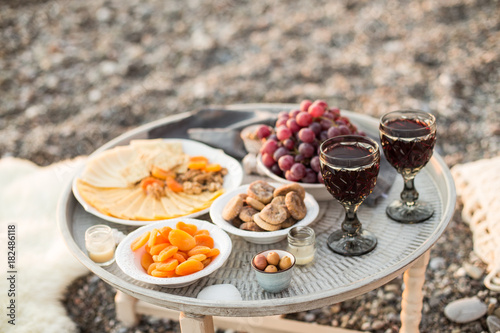 Outdoors picnic with wine, cheese, grapes and dried fruits