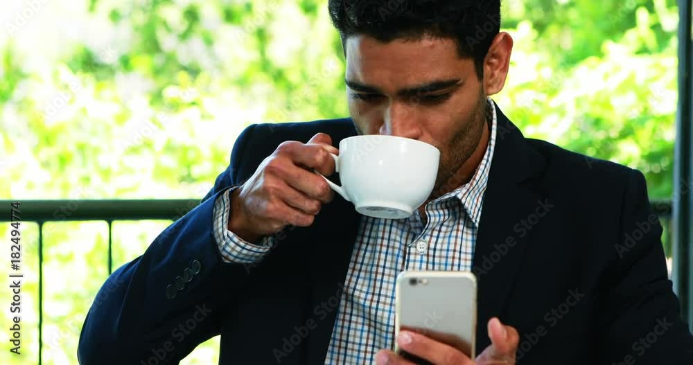 Businessman using mobile phone while having coffee Businessman using mobile phone while having coffee