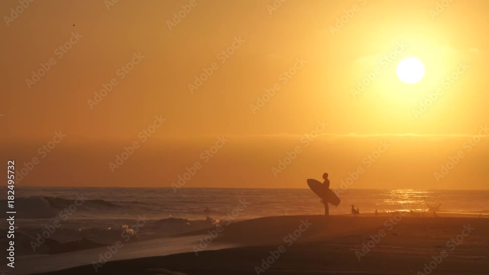 Surfer watching sunset on the beach, California Surfer watching sunset on the beach, California