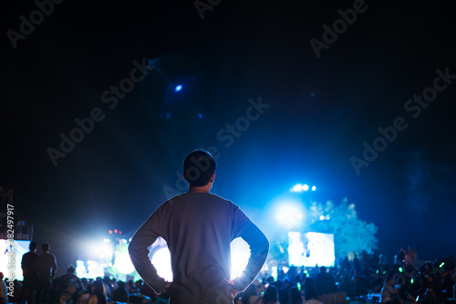 a man with crowded people enjoying outdoor night music festival