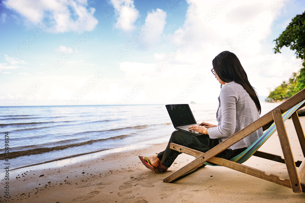 usiness woman using a laptop beside the beach
