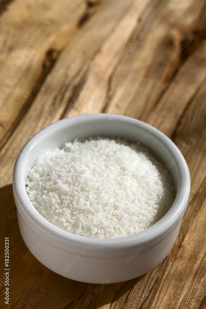 Grated coconut in small on wood, photographed with natural light (Selective Focus, Focus one third into the grated coconut)