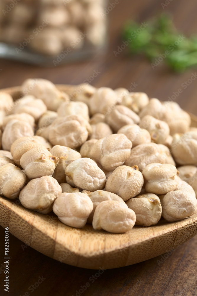 Raw chickpeas or garbanzo beans on small wooden plate, photographed with natural light (Selective Focus, Focus one third into the image) Raw chickpeas or garbanzo beans on small wooden plate, photographed with natural light (Selective Focus, Focus one third into the image)