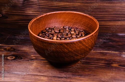 Roasted coffee beans in bowl on wooden table