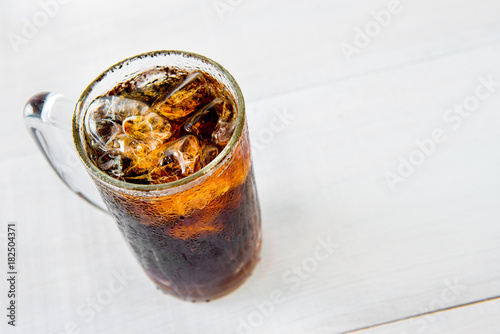 Glass of cola with ice on wood baord