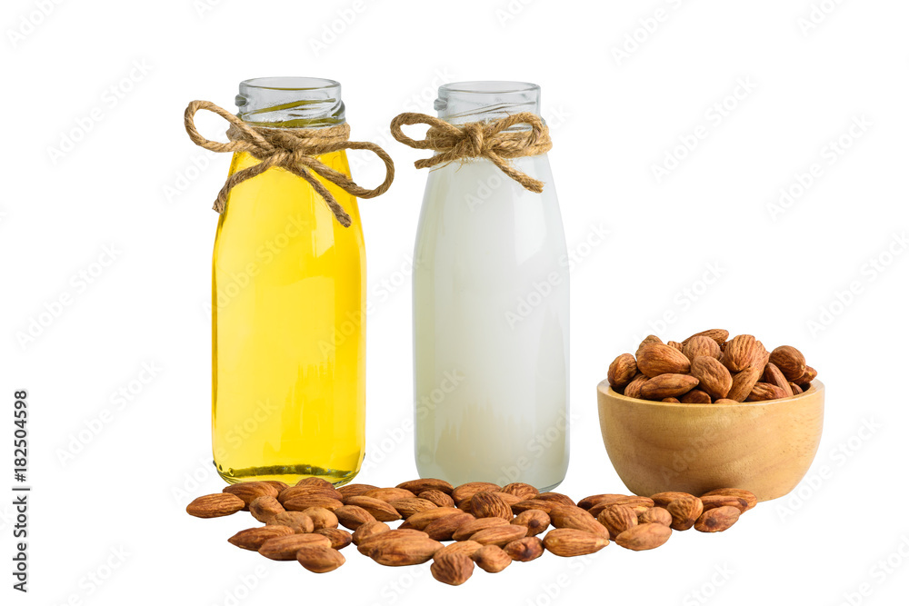 Bottle of almond milk and oil with Peeled almonds in wooden bowl isolated Bottle of almond milk and oil with Peeled almonds in wooden bowl isolated