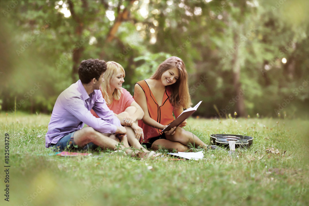 successful group of students with notebooks at the Park with a book and a guitar successful group of students with notebooks at the Park with a book and a guitar