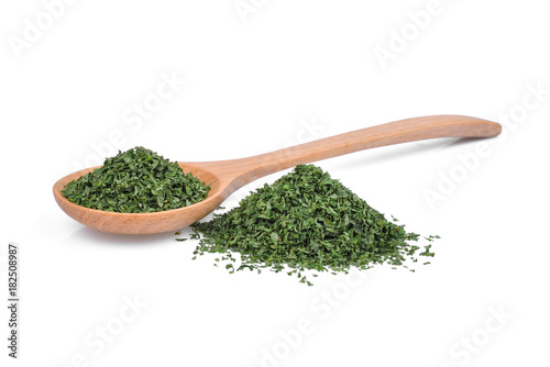 dried parsley leaf or petroselinum crispum in wooden spoon isolated on white background