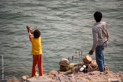 Two Indian fishermen fishing on river bank photo