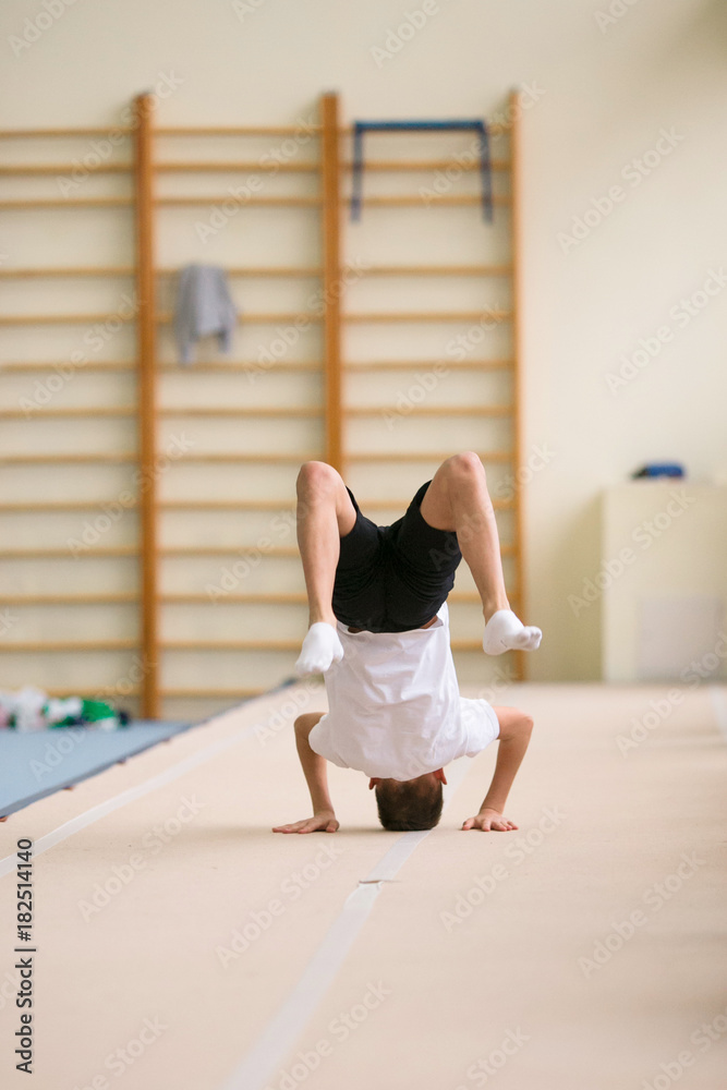 the young man performs gymnastic exercises in the gym. the young man performs gymnastic exercises in the gym.