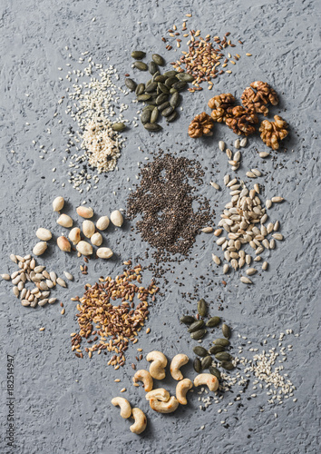 Superfood ingredients. Assortiment seeds and nuts on a gray background, top view. Flax seeds, sesame seeds, walnuts, sunflower seeds, cashews, pumpkin seeds, peanuts. Healthy food concept