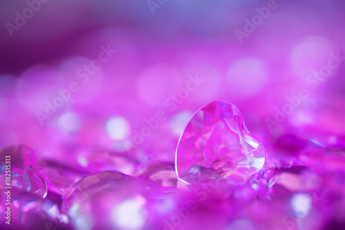 Many lilac little crystal hearts with bokeh background.