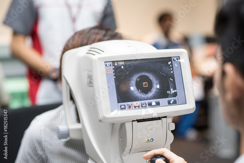 Cuadro en lienzo Woman looking at refractometer eye test machine in ophthalmology