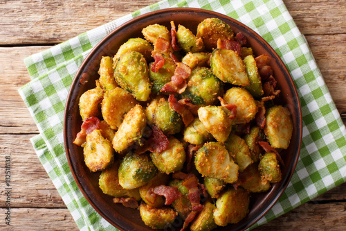 Delicious fried Brussels sprouts with crispy bacon close-up on a plate. Horizontal top view