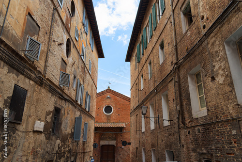 Beautiful medieval narrow street in the spring, Siena, Italy. Historic centre of Siena has been declared by UNESCO a World Heritage Site.