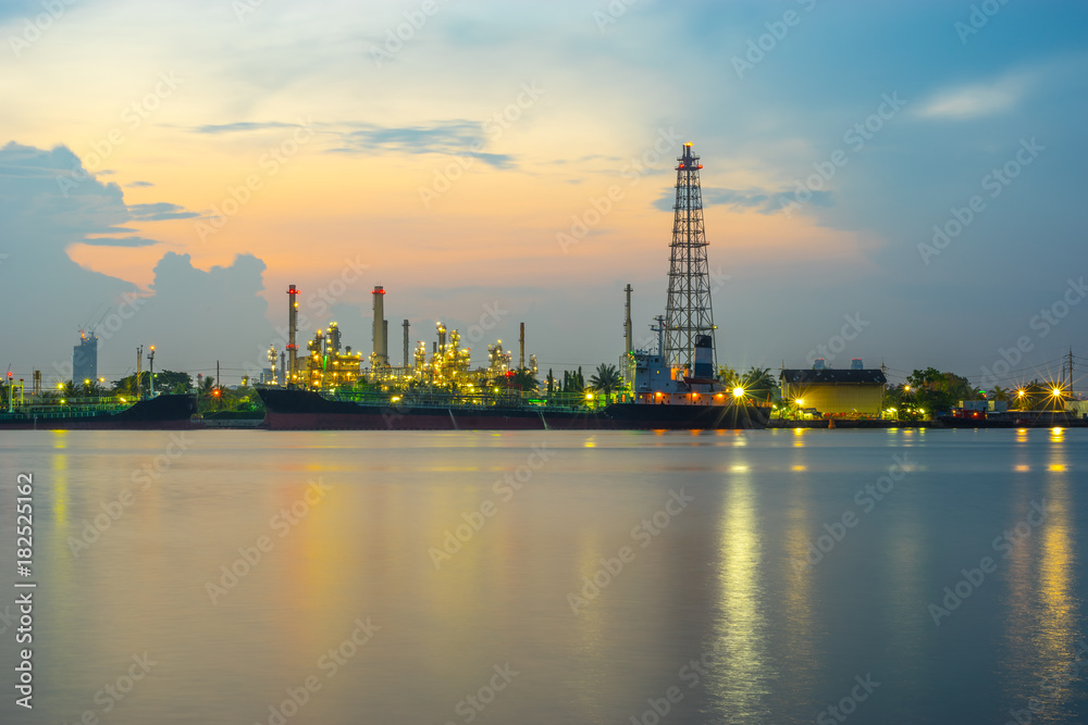 Oil refinery, tanker ship and petrochemical plant at morning time beside Chao Phaya river, Thailand. Smooth water and reflection.