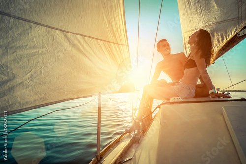 Romantic couple in love on sail boat at sunset under sunlight on